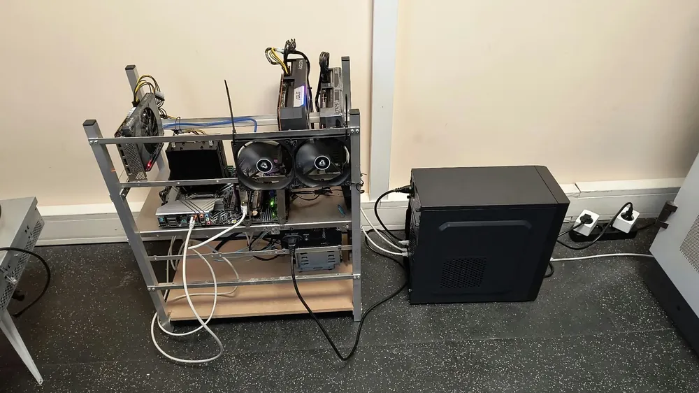 Serwer na otwartej ramie: karty graficzne Radeon, dwa wentylatory przypięte trytytkami, plątanina kabli, obok czarna obudowa komputera